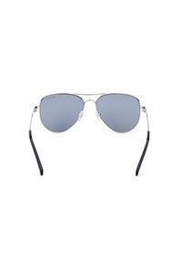 Gafas de sol aviador de metal con lentes tintados en azul, marco delgado en plata y patillas de plástico negro. Cuenta con almohadillas en la nariz para mayor comodidad.