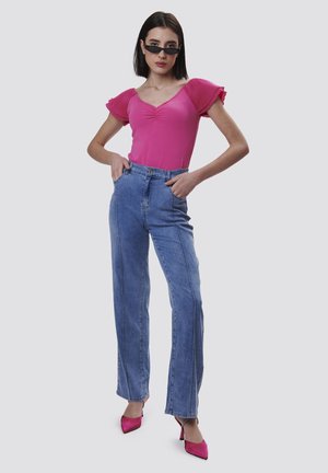 Body rose ajusté avec des manches volantes, associé à un jean droit taille haute en denim bleu clair et des escarpins roses pointus.