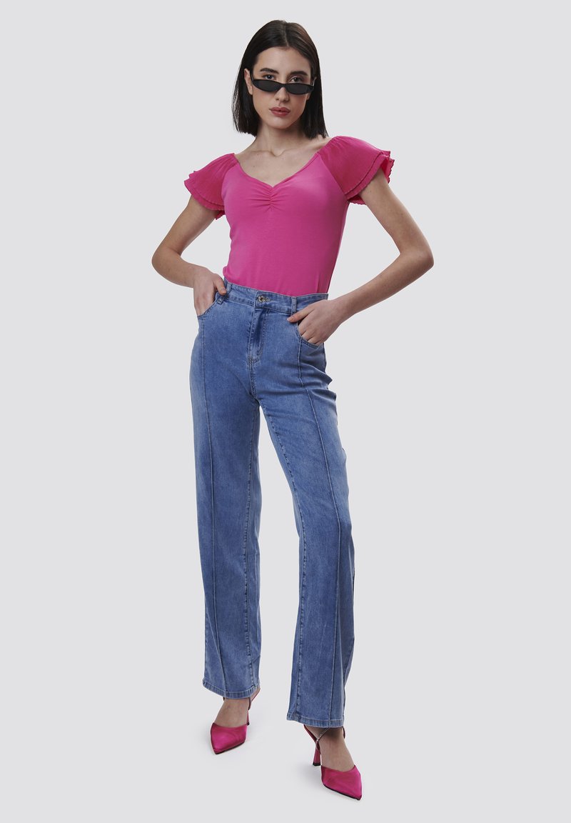 Tight pink body med voluminøse ærmer, parret med højtaljede lyseblå denim straight-leg jeans og spidse pink hæle.
