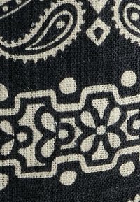Tessuto a motivi nero e crema con disegni floreali e paisley. Tessitura strutturata con dettagli intricati e colori a contrasto.
