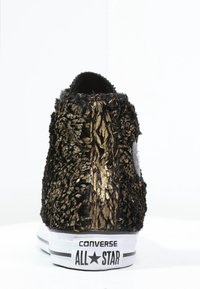 Černo-zlaté texturované vysoké tenisky s chlupatým materiálem, bílou podrážkou a černým logem na patě.