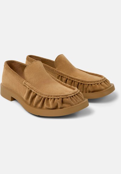 Paar braune Wildleder-Mokassin-Loafer mit gesammelten Nahtdetails und flachen Gummisohlen vor weißem Hintergrund.