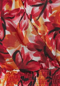 Tejido con estampado floral en rojo, naranja y negro, con una superficie texturizada. El diseño incluye grandes flores con contornos contrastantes.