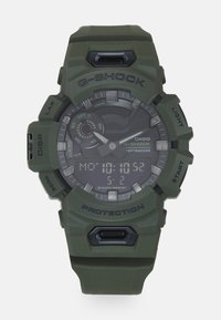 G-SHOCK digital klokke med et olivengrønt resinhus og -rem. Har en svart urskive, flere urvisere og sølv detaljer for tidsvisning.