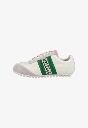 Witte sneaker met grijze suède neus, groene streep en zwarte tekst, witte veters en roze gevoerde kraag, gezien vanaf de zijkant.