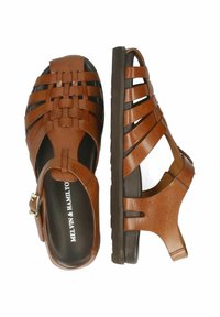 Brązowe skórzane sandały z plecionym paskiem, otwartym palcem i klamrą na kostce. Teksturowana cholewka oraz solidna czarna podeszwa zapewniają stabilność.