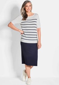 Gestricktes Kurzarm-Oberteil in Hellgrau mit marineblauen Streifen, kombiniert mit einem marineblauen Midirock. Getragen mit weißen Sneakers und einer entspannten Passform.