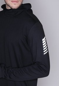 Musta pitkä hiha huppari, jossa on teksturoitu kangas, vasemmassa hihassa heijastava nauhadesign ja korkea kaulus.