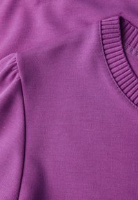 Maglione viola caratterizzato da un tessuto testurizzato, colletto a coste e maniche a sbuffo. Il materiale è liscio e leggermente elasticizzato.
