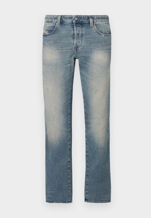 Svetlo modre jeans hlače ravnega kroja z odrgninami, petimi žepi in zaponko z gumbom. Tkanina kaže rahle znake obrabe in izbledele predele.