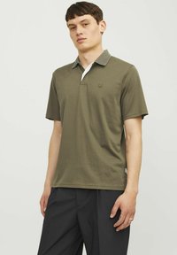 Olivová polokošeľa s kontrastným sivým golierom, bielou légou a malým logom na hrudi. Mäkký bavlnený materiál.