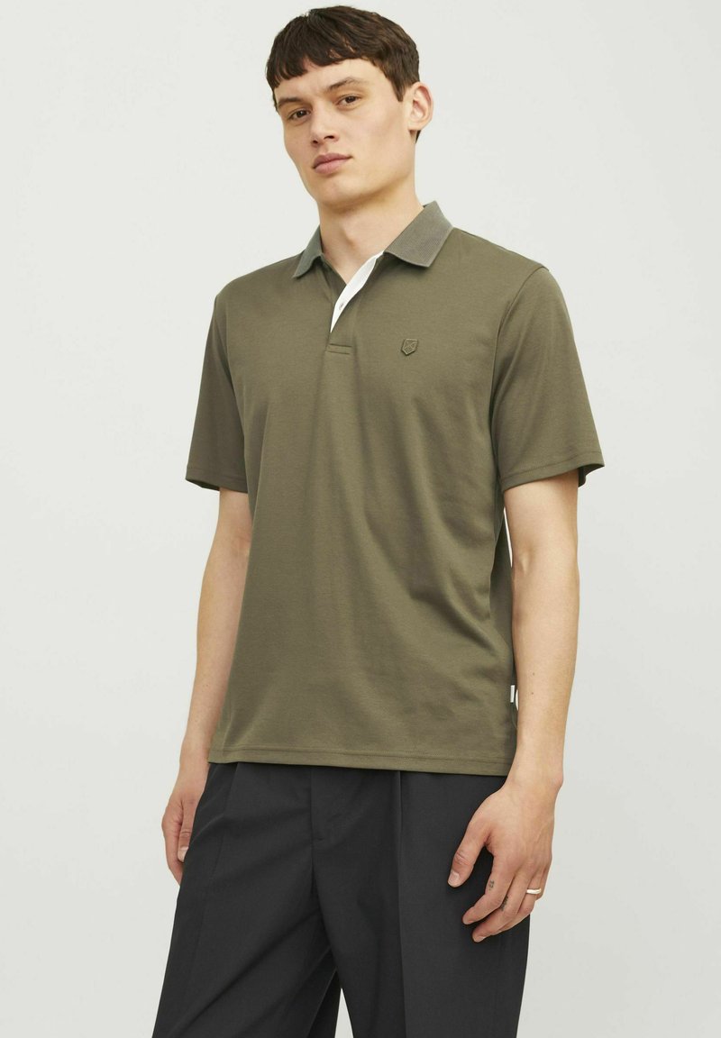 Olivová polokošeľa s kontrastným sivým golierom, bielou légou a malým logom na hrudi. Mäkký bavlnený materiál.