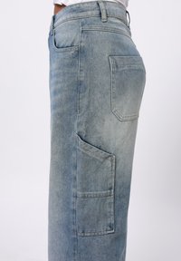 Lyseblå denimskjørt med sidelomme, rett snitt og subtilt falmet tekstur. Standard midje med beltehemper.