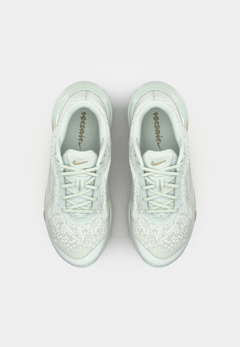 Zapatillas deportivas verde claro con parte superior texturizada, diseño con cordones y acentos dorados. Cuentan con un cuello acolchado y una suela de amortiguación visible.