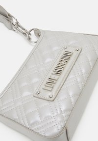 Kwiatowy srebrny torebka wykonana z materiału syntetycznego, z wyraźną płytką logo "LOVE MOSCHINO", srebrnymi akcesoriami i regulowanym paskiem.