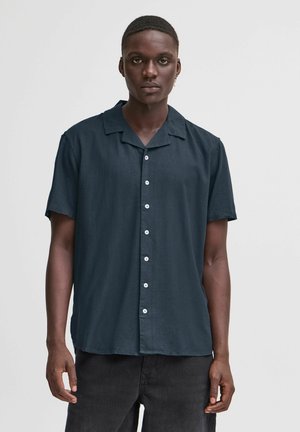 Camisa de manga corta, color azul oscuro, fabricada con un tejido ligero, que presenta un collar, cierre de botones en el frente y botones blancos con una textura suave.