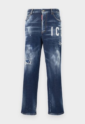Dark blue denim jeans with distressed patches, light paint splatters, and bold white lettering. Straight leg design with a classic fit.