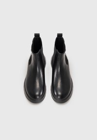 Bottes Chelsea noires en cuir avec une finition lisse, des panneaux latéraux élastiques, un bout rond et une languette à l'arrière ; design minimaliste.
