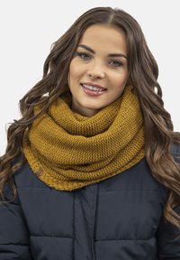 Căciulă tricotată de culoare muștar cu un model texturat, design stratificat și o etichetă din piele. Purtați-o peste o jachetă puf din culori închise.