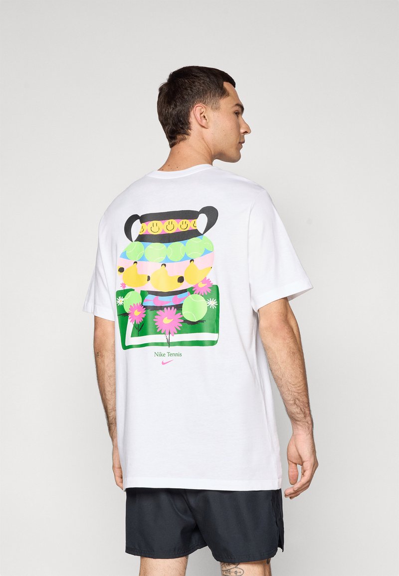 Camiseta blanca de algodón con un gráfico colorido en la parte trasera, que representa un jarrón con caras sonrientes, pelotas de tenis y flores.