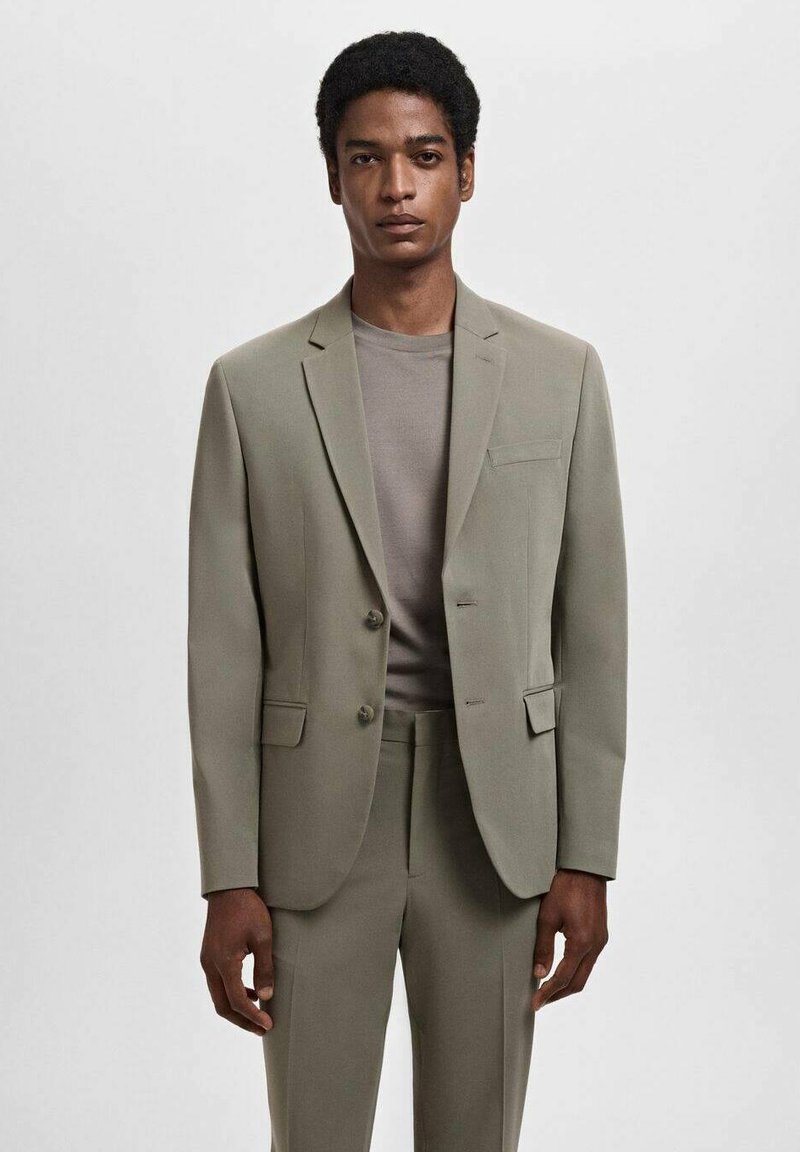 Light green suit jacket with two buttons, notched lapels, and a chest pocket, paired with a grey t-shirt. Plain, tailored fit.