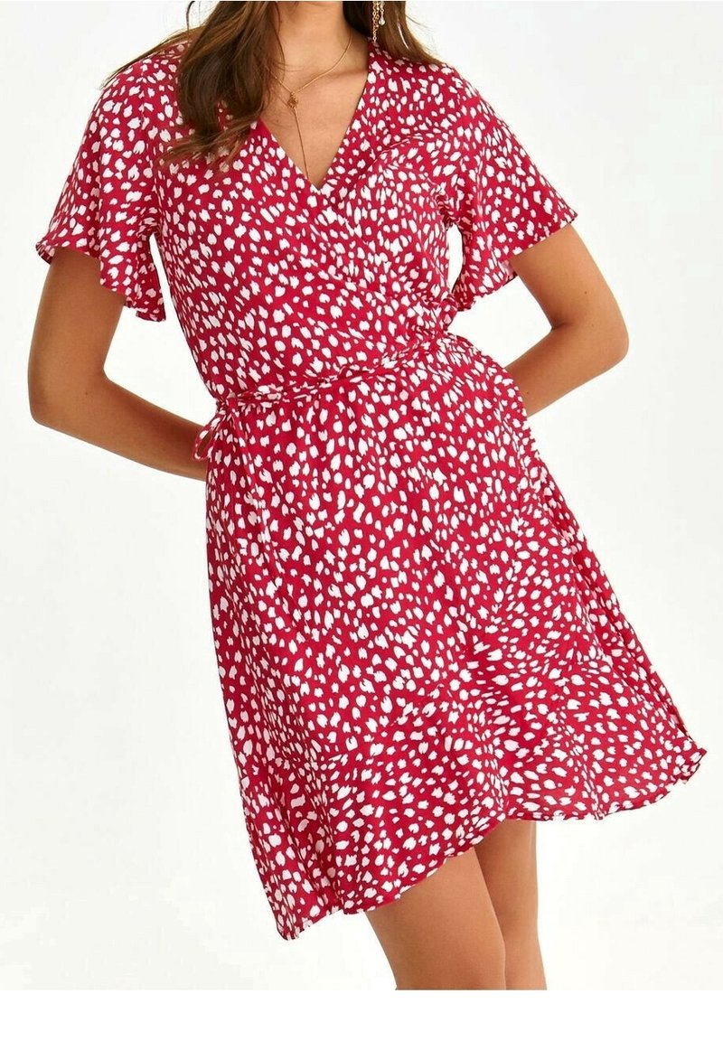 Rotes Wickelkleid mit kurzen, gerafften Ärmeln, das ein weißes abstraktes Muster aufweist. Leichter Stoff und eine Taillenschnürung.
