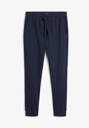 Pantalones de chándal de algodón azul marino con cintura elástica, cordón ajustable, bolsillos laterales y un pequeño logo rojo en la pierna izquierda. Textura suave.