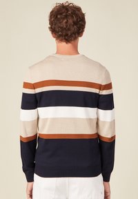Pull en tricot aux rayures beiges, brunes, blanches et marine. Il dispose de manches longues, d'un col rond et de poignets et ourlet côtelés. Texture douce.