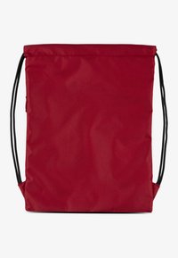 Piros szövet táska egyszerű dizájnnal, két fekete húzózsinórral és téglalap alakú formával. Matt felület, további minták nélkül.