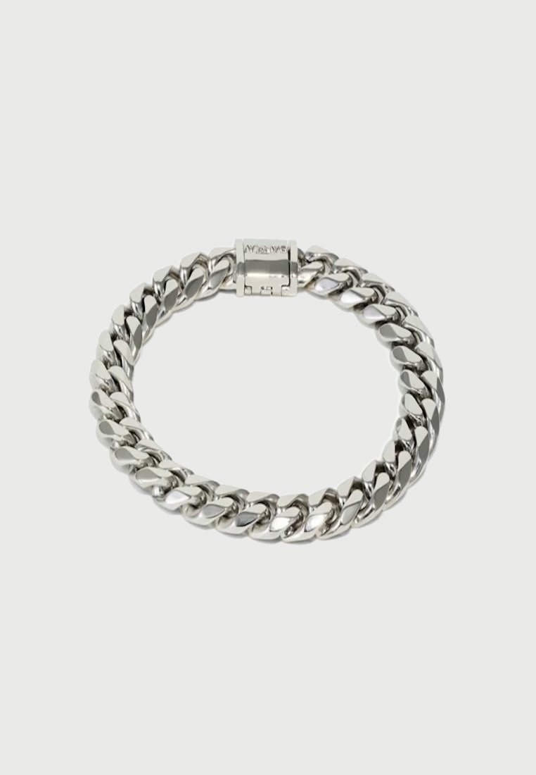 Un bracelet en argent poli, composé de maillons gourmette épais et entrelacés, avec un fermoir boîte, disposé en cercle sur un fond clair uni.