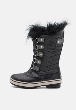 Black waterproof winter boot with fur trim, quilted textile upper, lace-up design, rubber sole, and side logo detail.