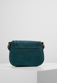 Torba na ramię z miękkiej skóry w kolorze morskim z zaokrąglonym kształtem, przednią klapką i złotymi elementami. Gładka faktura z przeszyciami.