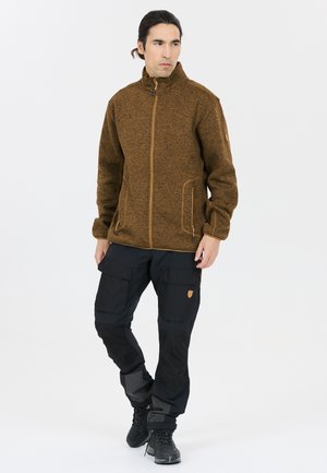 Brown textured jacket with high collar, zip closure, and side pockets. Paired with black cargo pants featuring multiple pockets and accents.