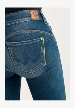 Jean en denim bleu foncé avec une patch en cuir, des accessoires dorés, et un design de poche arrièreDistinctif avec un motif en zigzag.