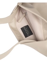 Borsa a spalla beige realizzata in materiale sintetico liscio. L'interno presenta una fodera morbida, una tasca con zip e un'etichetta nera del marchio.