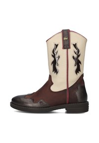 Bottes de cow-boy en cuir marron et crème avec un bout pointu, des découpes décoratives en forme de flammes et un talon texturé marron. Des surpiqûres rouges soulignent le design.
