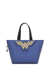 Blå toteväska med svarta handtag, försedd med en guldig Wonder Woman-emblem på framsidan. Materialet ser glänsande och slätt ut, utan synliga mönster.