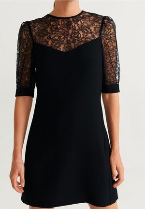 Schwarzes Kleid mit transparentem floralen Spitzentop und Ärmeln, die oberhalb des Ellbogens enden, einem festen, eng anliegenden Oberteil und rundem Ausschnitt.