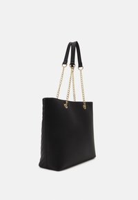 Black tote bag with a smooth exterior, featuring gold chain accents and leather straps. Side has a quilted texture detail.