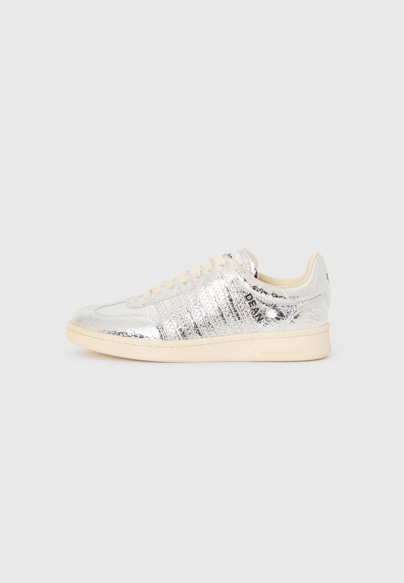 Silver metallic sneaker with textured upper, cream rubber sole, and light beige laces. Features horizontal ridges and logo detail.