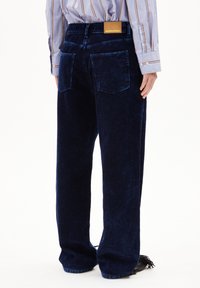 Marinblå kordflöjtbyxor med rak passform, synlig sömnad, två bakfickor och en märkesläderdyna på midjan.