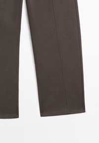 Mørkebrune bukser med lige snit, der har synlige sømme og detaljer i sidesømmen. Glat tekstur og ingen synlige mønstre.