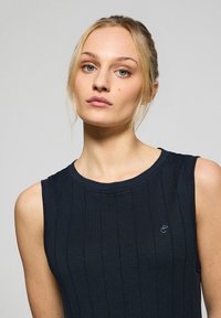 Czarny bezrękawnik z prążkowaną teksturą, okrągłym dekoltem i małym, subtelnym logo w jasnoniebieskim kolorze po lewej stronie klatki piersiowej.