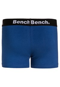 Kék boxer nadrág rugalmas anyagból. Fekete derékrésszel rendelkezik, amelyen fehér "Bench" márkázás található. Egyszerű dizájn, további minták nélkül.
