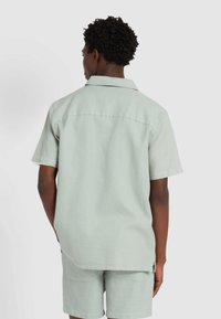 Korte mouwen overhemd met kraag en short-set in lichtgroene textuurstof, met een subtiel patroon en een afgeronde zoom.