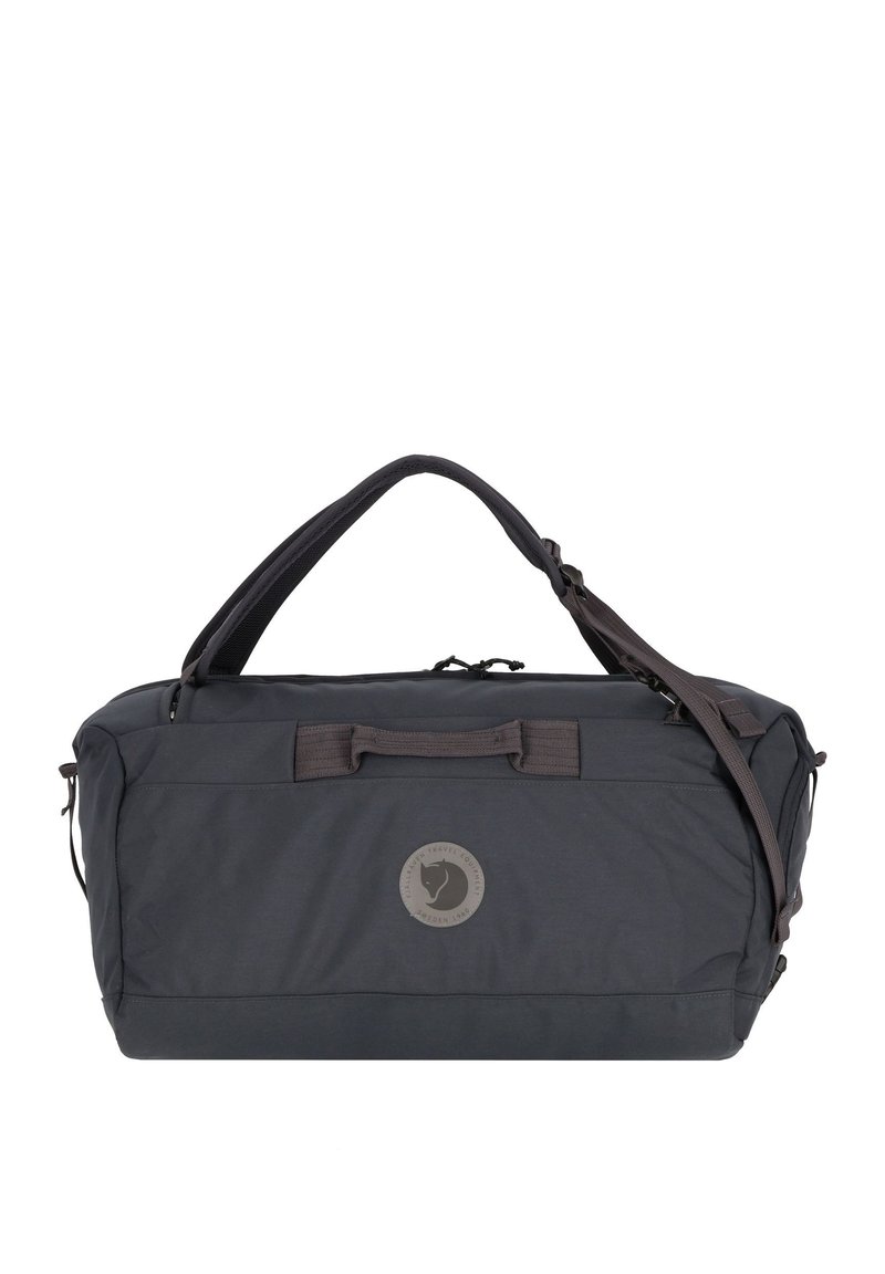 Bolsa de viaje de tela negra con un logo redondo. Cuenta con dos asas y una correa de hombro ajustable. La superficie es suave con un acabado mate.