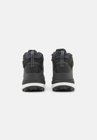 Zapatos de senderismo negros con un upper texturizado, un collarín acolchado para el tobillo y una suela resistente con un dibujo pronunciado para mayor tracción.
