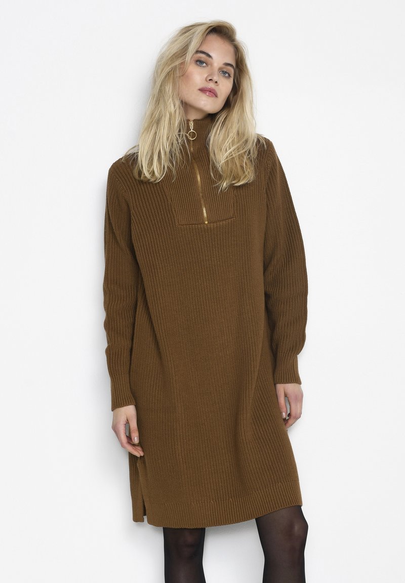 Robe marron côtelée avec un col haut et un cou zippé, dotée de manches longues et de fentes sur les côtés. Confectionnée en tissu tricoté texturé.