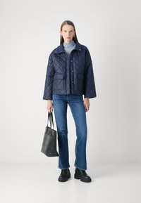 Σακάκι ναυτικού ύφους με επένδυση και κούμπωμα με κλιπ, δύο μπροστινές τσέπες και σχέδιο με γιακά, συνδυασμένο με ανοιχτού μπλε ζιβάγκο, μπλε τζιν και μαύρα μποτάκια.