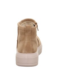 Bota de tobillo de ante beige con un suave forro interior, que presenta una suela de goma blanca y un cierre de cremallera en la parte posterior.